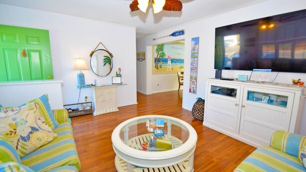 A living room with a round coffee table, striped sofas, a television, and a green door. - Twin Tree Road 511 3 Bedroom Home by RedAwning (Ocean City)