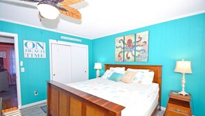 A bedroom with a bed, two bedside tables, a ceiling fan, and artwork on the wall. - Twin Tree Road 511 3 Bedroom Home by RedAwning (Ocean City)