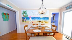 A dining area with a wooden table, chairs, and a bench. A beach-themed mural is on the wall behind the table. - Twin Tree Road 511 3 Bedroom Home by RedAwning (Ocean City)
