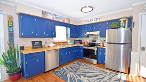 A modern kitchen with blue cabinets, stainless steel appliances, and a wooden countertop. - Twin Tree Road 511 3 Bedroom Home by RedAwning (Ocean City)