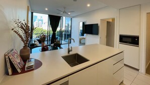 A modern kitchen with a large island, a built-in microwave, and a flat-screen TV mounted on the wall. - Charming Urban Retreat (South Brisbane)