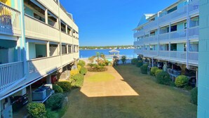 A beachfront hotel with multiple balconies, a central lawn, and a view of the sea. - Beach Access, Lagoon, Fishing Pier and Pool (Gulf Shores)