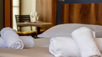 Cama bem arrumada com toalhas brancas e cabeceira de madeira.