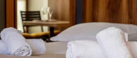 A neatly made bed with white towels and a wooden headboard.