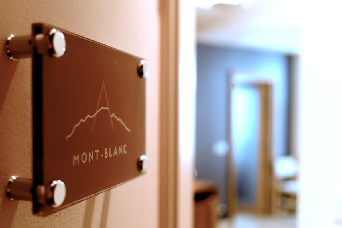 Ein Schild mit Bergmotiv und dem Text 'MONT-BLANCH' an einer Wand.