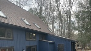A blue house with a deck, covered tables, and a wooden fence.