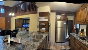 A spacious kitchen with a large island, a dining area with a high ceiling, and a cozy seating area with a fireplace.