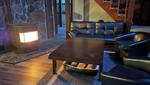 A cozy living room with a stone fireplace, leather sofa, and a wooden coffee table.