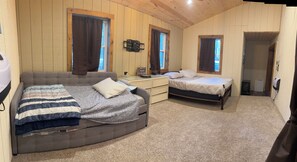 Una habitación con dos camas, un sofá, una mesita y un espejo.