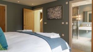 Een slaapkamer met een bed, een badkamer met douche, en een deur die naar een andere kamer leidt.