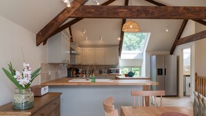 Een moderne keuken met houten balken, witte kasten en een groot raam.