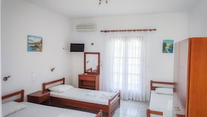 A hotel room with two single beds, a wooden wardrobe, a mirror, a television, and a window with curtains. - Apartments Eytyxia (Kassandra)