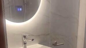 A modern bathroom with a round mirror, a white sink, and a toilet. - Apartments Eytyxia (Kassandra)