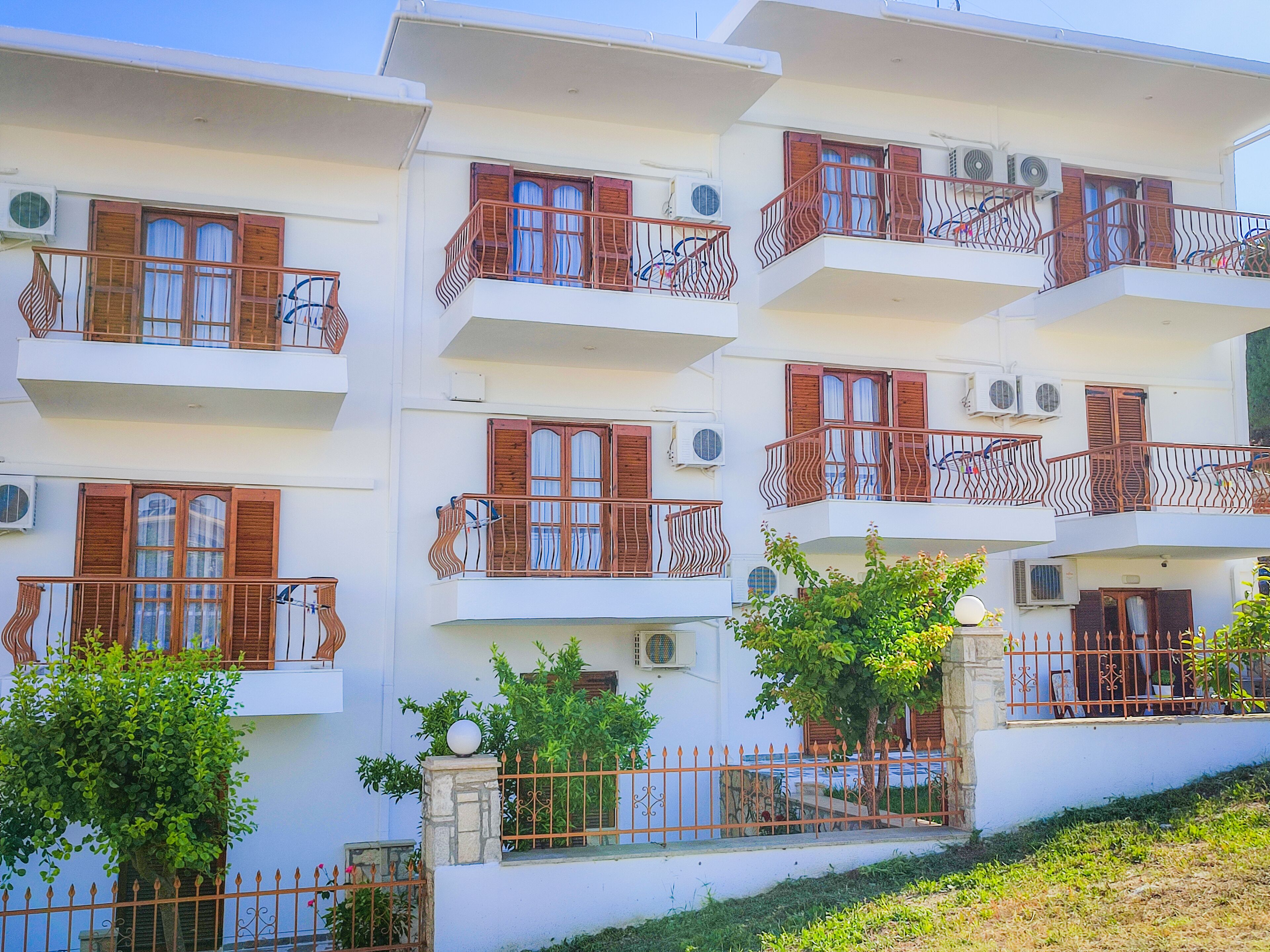 Un immeuble à plusieurs étages doté de balcons, de climatiseurs et d’une base en pierre.