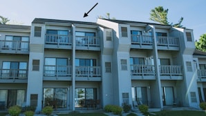 Un edificio de apartamentos de varios pisos con balcones, puertas de vidrio corredizas y zonas de estar al aire libre.