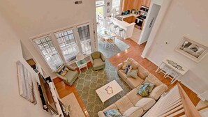 A spacious living area with a large window, a kitchen with wooden cabinets, and a dining area with a table and chairs.