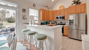 A modern kitchen with wooden cabinets, stainless steel appliances, and a central island with bar stools.