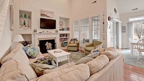 A spacious living room with a fireplace, comfortable seating, and a television.