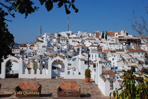 Une ville perchée sur une colline, avec des bâtiments blancs et des toits en tuiles de terre cuite.