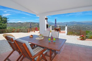 Une terrasse avec une table et des chaises, une vue sur les montagnes et une clôture en bois.