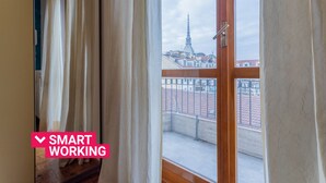 A room with a large window, curtains, and a view of a cityscape with a tall building. - Casa Antonelli by Wonderful Italy (Torino)