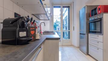 A modern kitchen with a coffee machine, a stove, and a refrigerator.