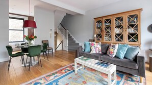 Un salon comprenant un canapé, des fauteuils, une table basse, une bibliothèque et un escalier.