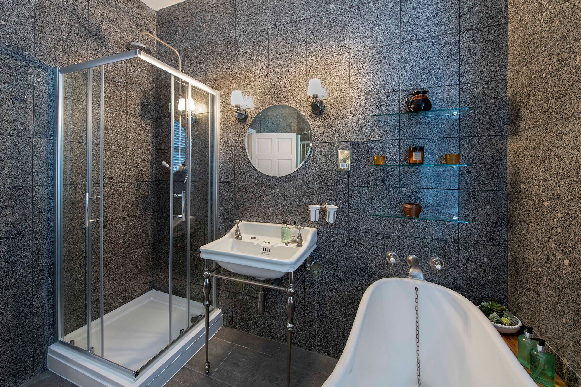 A modern bathroom with a glass-enclosed shower, a white sink, and a freestanding bathtub.