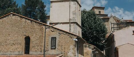A historic building with a bell tower, stone walls, and a paved street with traffic cones.