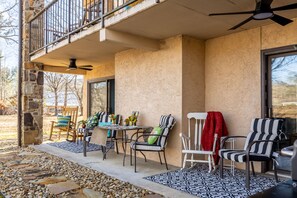 Relax in a serene outdoor seating area with a stone wall, balcony, and comfortable seating.