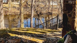 A riverside pathway with a stone border, a metal railing, and trees in the background. - Just steps from your private patio to the river (Townsend)