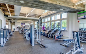 Una palestra con macchinari cardio, attrezzi per pesi e manubri.