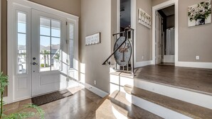 Un intérieur moderne avec un escalier, une porte portant une inscription et une vue sur l’extérieur.