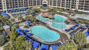 Un hôtel doté de plusieurs piscines, de chaises longues et de parasols.