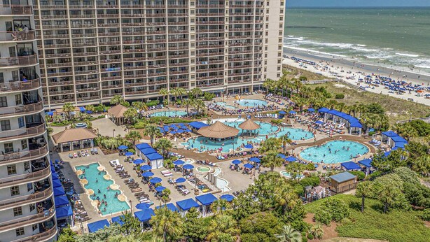 Un hôtel doté de plusieurs piscines, d’une plage et d’un immeuble de grande hauteur.