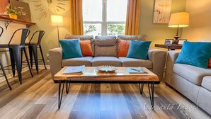 A living room with a sofa, coffee table, and a dining area with chairs.