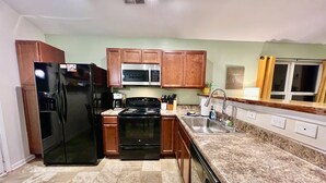 A modern kitchen with a refrigerator, stove, microwave, and sink.