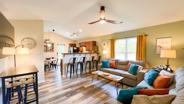 A modern living room with a sofa, coffee table, and a dining area with chairs and a table.