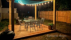 A wooden deck with a covered patio area, featuring a table and chairs, surrounded by a wooden fence.
