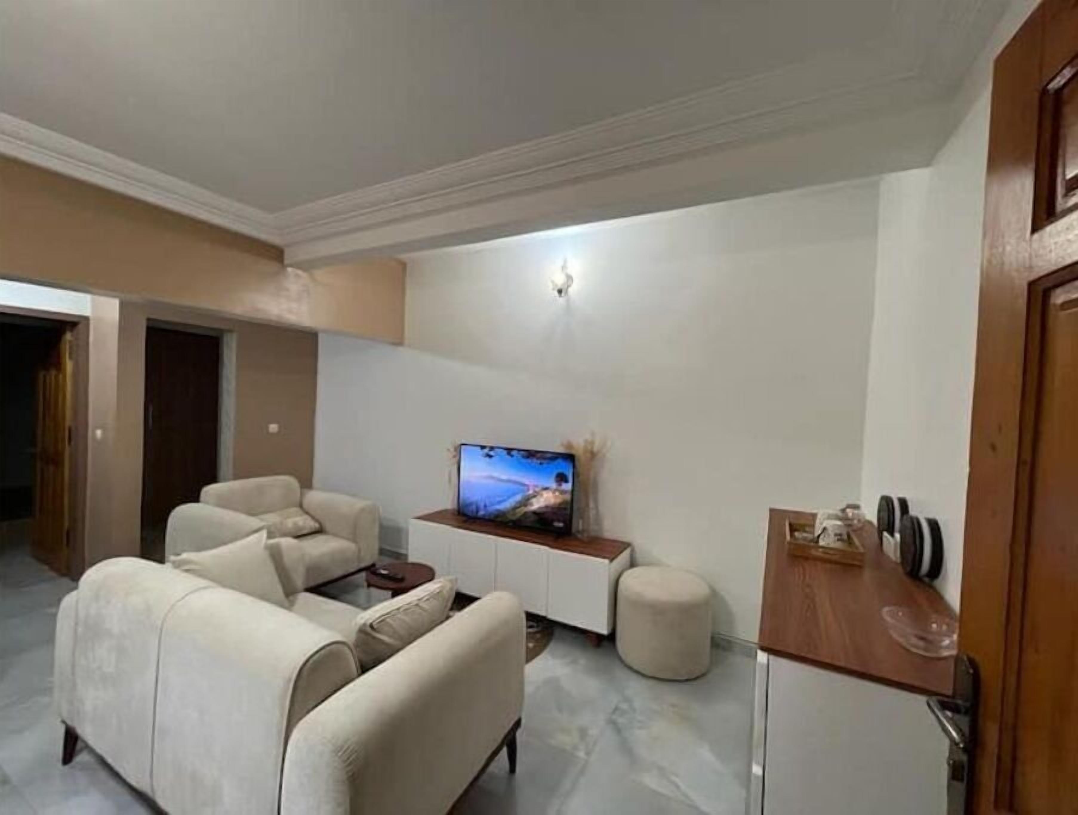 A modern living room with a sofa set, a coffee table, a television, and a small wooden side table.