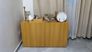 Ein Holzkabinett mit einem weißen Teekessel, einer schwarzen Tasse und einem weißen Teller darauf.
