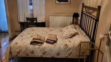 A bedroom with a bed, a chair, a radiator, and a lamp.