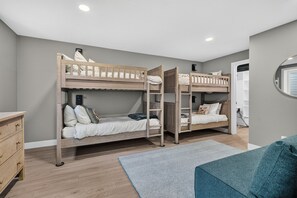 A room with bunk beds, a dresser, and a window.