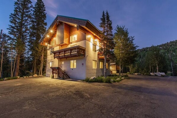 A two-story lodge with a balcony, wooden exterior, and a driveway leading to the entrance.