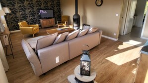 A living room with a beige sofa, yellow armchairs, a TV, and a wood-burning stove. - Createur DE Souvenirs (Chartres)