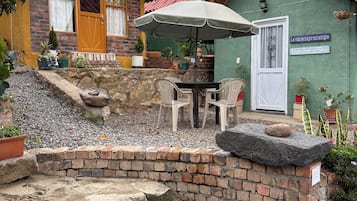 A rustic building with a brick patio, outdoor seating, and potted plants.