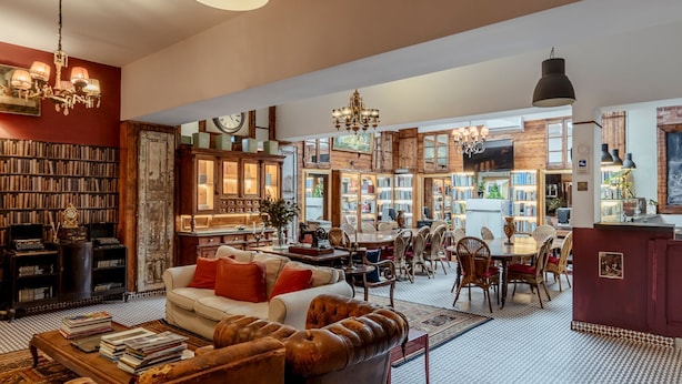 Amplia sala de estar con una gran estantería, una zona de estar acogedora y un comedor.