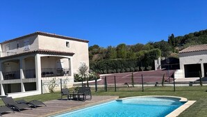 Ein Pool mit Liegestühlen und ein Gebäude mit einem Ziegeldach im Hintergrund.