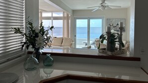 Una habitación con vista al océano, ventilador de techo y una mesa con adornos.
