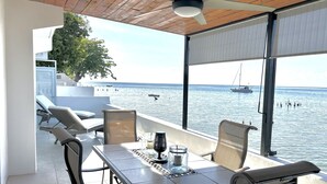 Un balcón con mesa, sillas y vista al mar.